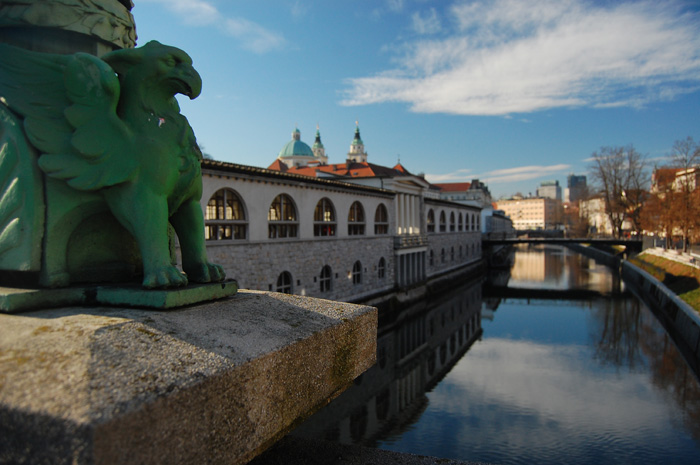 The lampposts on the Dragon Bridge depict griffins. In the background you can see the colonnade of the central market and The Cathedral.