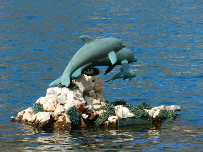 the dolphin family sculpture by the stairs at port