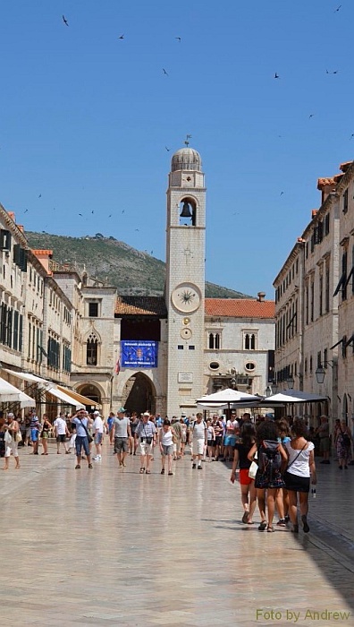 The Stradun (Placa) avenue, in the background the City Bell Tower with the Green Ones and the front of the Sponza Palace to the left